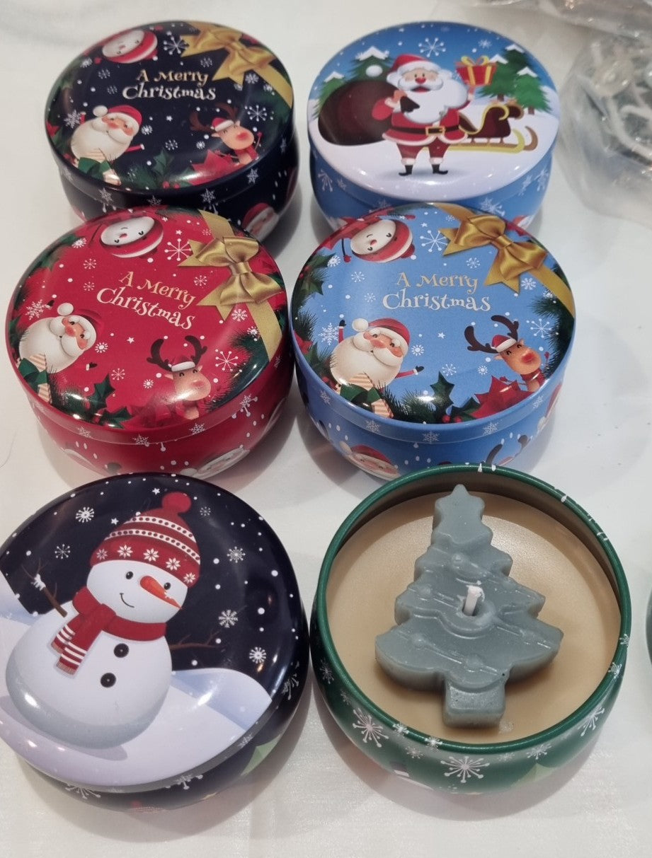 Bougies en boîtes rondes aux motifs de Noël, dont une ouverte avec un décor de sapin.